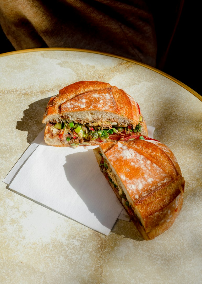 Tender roast beef sandwich served on a soft bun. The sandwich is layered with thinly sliced roast beef coated in savory sauce or gravy